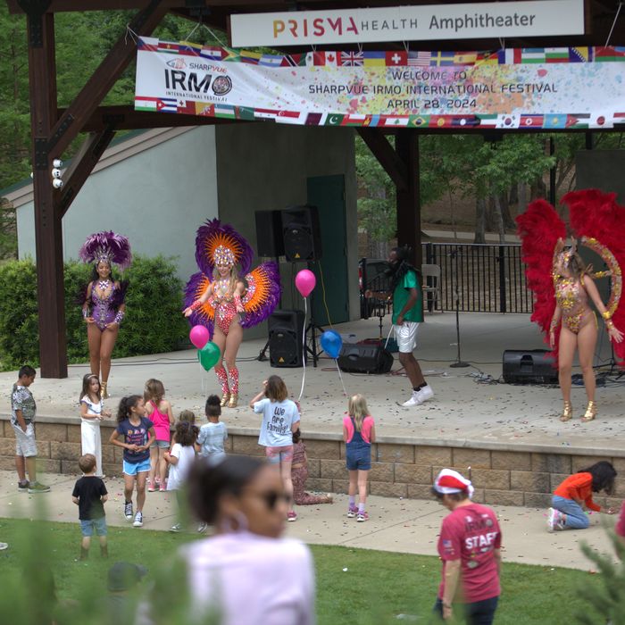 Samba dancers in feathered costumes with children dancing